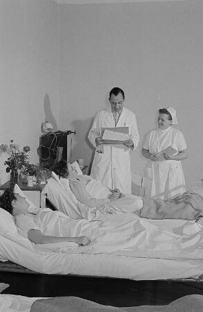 Ein Arzt, eine Krankenschwester sowie zwei Patientinnen bei der Visite in der Betriebspoliklinik der Transmasch Leipzig