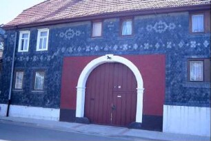 verschiefertes Bauenhaus mit rundbogiger, überbauter Torfahrt