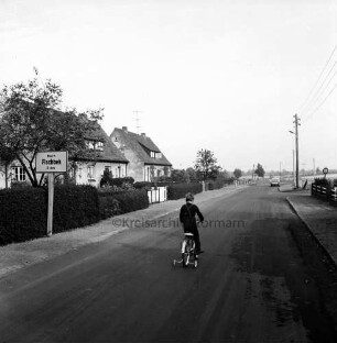 Fischbeker Straße: Kreisstraße in Richtung Fischbek: im Vordergrund Kind auf Fahrrad: links Siedlungshäuser mit Vorgärten: davor Ortsausgangsschild