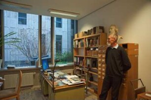 Porträt Perk Loesch, Fachreferent der SLUB : Porträt des Kunstwissenschaftlers Perk Loesch, Fachreferent und von 1996 bis 2019 Leiter der Handschriftenabteilung an der Sächsischen Landesbibliothek – Staats- und Universitätsbibliothek Dresden (SLUB). Aufnahme in seinem Dienstzimmer mit Büste Karl Christian Friedrich Krause (1815)
