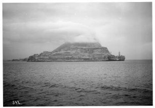 Gibraltar: Upper Rock mit Leuchtturm. Blick vom Wasser auf felsige Küste der Insel Gibraltar mit Leuchtturm