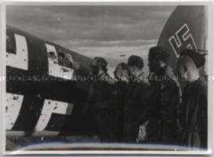 Deutsche Soldaten an einem gelandeten beschossenen Kampfflugzeug der deutschen Luftwaffe