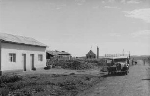 Adi Kwala : Blick auf Häuser und Straße von Adi Kwala, im Hintergrund eine katholische Kirche.