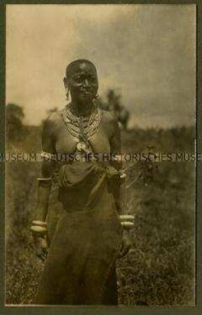 Frontalansicht einer stehenden, alten Wadschagga-Frau mit traditionellem Schmuck