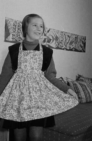 Ein Mädchen führt eine Schürze mit Batikmuster vor