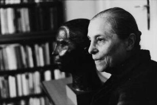 Porträtbüste Lotte Loebinger : Lotte Loebinger im Profil nach links vor ihrer Porträtbüste (Bronze; vor 1974) in ihrer Wohnung in Berlin