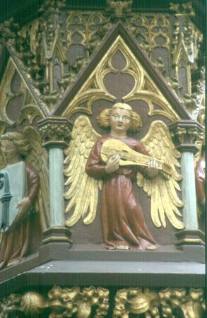 Basel, Fischmarkt. Fischmarktbrunnen, Fialensäule als Brunnenstock. Roter Sandstein, gefaßt, vergoldet; um 1380 (Kopie 1908 aufgestellt; Original in der Barfüsserkirche - Historisches Museum Basel). Unterstes Figurenband mit Engelsreigen in Wimpergen. Detail: Engel mit Stadtwappen und musizierender Engel mit Mandora