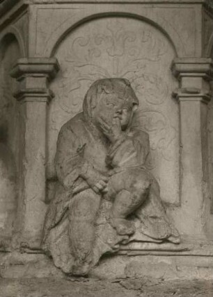 Döbeln, Nicolaikirche, Taufstein, Detail des Reliefs : Kind (Daumenlutscher), Stichbogenöffnung im Unterbau, 1603, Sandstein