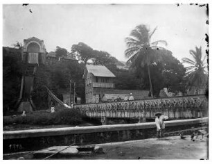 Fort de France, Martinique. Blick auf Kanalbrücke mit Touristen und Wasserfall im Bildhintergrund, vorn einheimischer Arbeiter