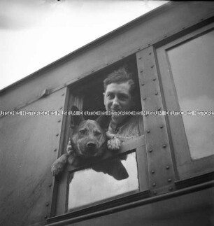 Ein Mann und ein Schäferhund ("Rolf") im Fenster eines Zuges