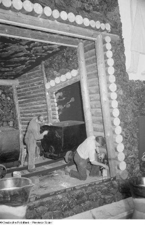 Arbeiter während des Aufbaus eines Messestandes in Form eines Stollens (Bergwerk) mit Loren