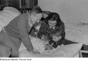 Porträt einer Frau, eines Mannes und einem kleinen Jungen, der einem Säugling die Flasche gibt