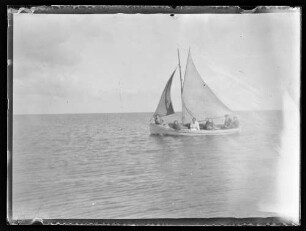 Kleines Segelboot mit mehreren Personen an Bord auf Meer oder großem See