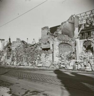 Blick über Gebäudereste und gestapelte Steine gegen Ruine der Reformierten Kirche und Neues Rathaus