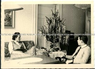 Ehepaar sitzt am Weihnachtsbaum