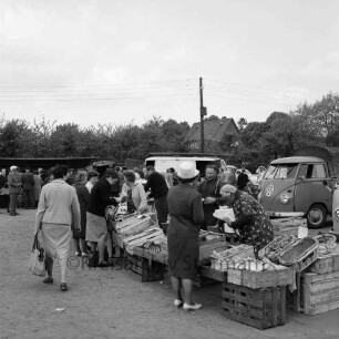 Wochenmarkt: Marktplatz [später Rathausplatz]: Marktstände, Verkäufer, Kunden: alte Verkäuferin beim Abwiegen von Waren: Kleintransporter: hinten Strommast, Wohnhaus, Obstgärten