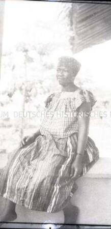 Afrikanische Frau auf einer Mauer sitzend