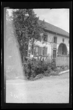 La Pariée (Dep. Vosges, Frankreich): Gebäude mit Tor und im Garten aufgehängter Wäsche (Distanzaufnahme)