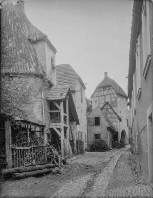 Sulzfeld am Main. Wohnhäuser an der Stadtmauer. Gasse mit Stampfbodendeckschicht und mittig angelegter gepflasterter Regenwasserrinne