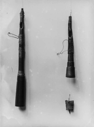 Musikinstrumente : Objektaufnahme zweier mit Rindsleder bezogenen Flöten aus Holz. Rechts unter den Flöten wurde eine Kuhglocke aufgehangen