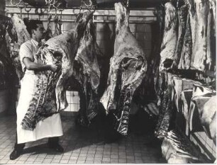 Hamburg. "Pro"-Fleischwarenfabrik. Ein Schlachter mit Schweinehälften im Kühlhaus