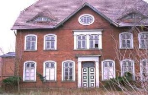 Dorfstraße 32: Bauernhaus aus Backstein: traufständiger Wohntrakt: Straßenfront mit Eingangsportal, Segmentbogen-Sprossenfenstern, Frontispiz mit ovalem Fenster, Fledermausgauben