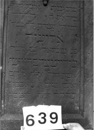 Grabstein 639 (Index: 99802941) Material: Sandstein Zustand: Maßwerk gebrochen/hinten stark verwitt. Maße HxBxT: 183x50x37 cm Beschreibung: Sock/St. m. verdacht. Giebel/Inschriftenfeld m. Spitzbogen und Maßwerk Symbolik: Maßwerk Besonderheit: Wortspiel mit dem Namen Elieser: Grabstein 639 (Detailaufnahme 3)