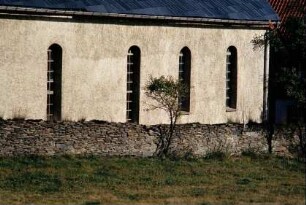 Kirchenschiff mit gotischen Fenstern, davor Mauer