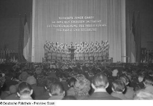 Blick vom Zuschauerraum auf Chor sowie Chorleiter auf einer Bühne bei einer Kulturveranstaltung in Halle II