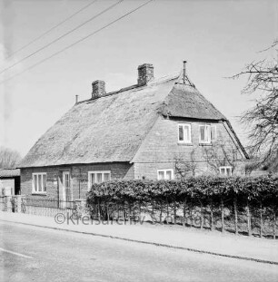 Dorfstraße: Ortseingang aus Richtung Ahrensburg: Haus mit Reetdach: davor Garten mit Hecke und Zaun