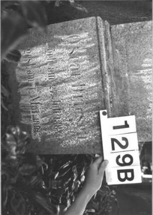 Grabstein 129 (Index: 100114305) Material: Kalkstein Zustand: stark verwittert mit Textverlust, Aufsatz fehlt Maße HxBxT: 137x39x19 cm Beschreibung: konische Stele, Sockel, Giebel mit Eckakroteren, eingetieftes Schriftfeld mit Rundbogen Besonderheit: Kindergrab: Grabstein 129B