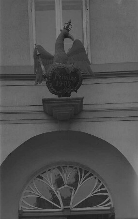 Tangermünde. Adlerapotheke, Hauszeichen über dem Portal, ein roter Adler mit goldener Krone und einem Zepter. Er hält einen grünen Blattkranz, der einen schwarzen Schild einrahmt mit der Aufschrift: Privileg 1494.