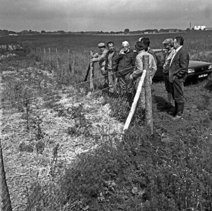 Biotop bei Ahrensburg: Koppel mit neuem Gehölz: vorn Zaun gegen Wildverbiss: rechts Personengruppe vom Amt für Land- und Wasserwirtschaft der Hansestadt Lübeck bei Besichtigung: dahinter Pkw: im Hintergrund Gewerbegebiet Beimoor