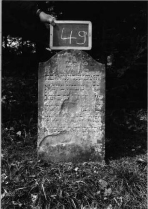 Grabstein 49 (Index: 100090651) Material: Sandstein Zustand: abgeblättert/verwittert mit Textverlust Maße HxBxT: 68x40x8 cm Beschreibung: Stele, Konvexbogenabschluß: Grabstein 49