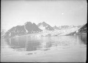 Dunkle Bergkette mit Schneefurchen am Fjord, Nordlandreise, Norwegen