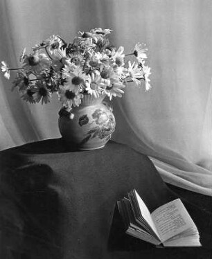 Stilleben. Sommerblumenstrauß in bemalter, bauchiger Vase und aufgeschlagenes Buch
