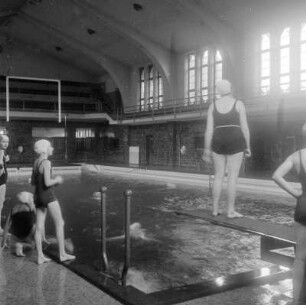 Frauen im Schwimmbad und auf dem Sprungbrett
