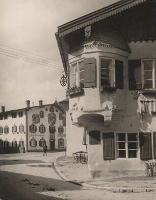 Oberammergau. Eckerker am Gasthof zum Stern, einem im 17. Jahrhundert errichteten Gebäudes. Im Hintergrund das von Franz Seraph Zwinck bemalte Wohn- und Geschäftshaus Dorfstraße 24