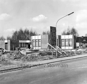 Lottbek: An der Lottbek: Evangelisch-lutherische Kirchengemeinde Hoisbüttel: Gemeindezentrum: Rohbau: davor Bauschild, Erd- und Sandhaufen sowie Baumaterial, Straßenlampe und Bauzaun: hinten Bäume und rechts Einfamilienhaus