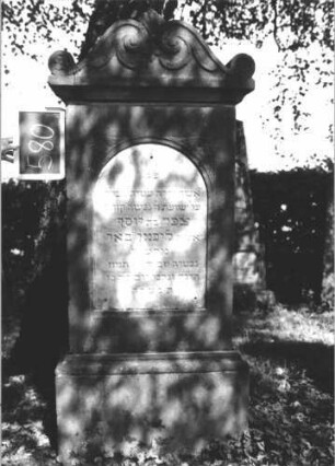 Grabstein 580 (Index: 100111460) Material: Sandstein, weiße Marmorplatte Zustand: gut Maße HxBxT: 161x71x23 cm Beschreibung: Stele, profilierter Sockel, Abdeckplatte mit Volutenaufsatz, Schriftplatte mit Rundbogenabschluß Symbolik: Voluten, Ranken, Blätter: Grabstein 580