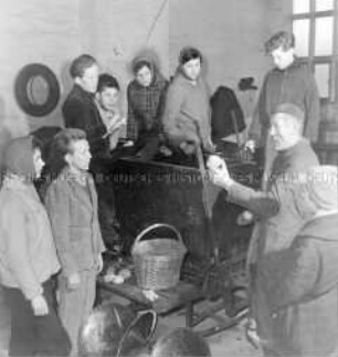 Ein LPG-Lehrausbilder der Landschule Buchholz erklärt die Kartoffel-Legemaschine