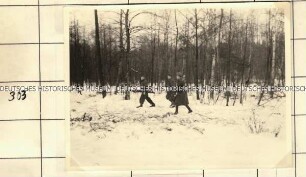Angehörige der Ordnungspolizei mit Säge in einem verschneiten Waldstück