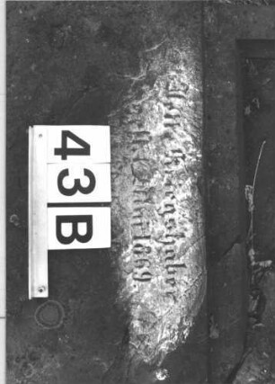 Grabstein 43 (Index: 100105904) Material: Sandstein Zustand: Stein liegend, quer gebrochen mit Textverlust Maße HxBxT: 133x60x17 cm Beschreibung: rechteckige Stele, Sockel, Schriftfeld eingetieft mit Spitzbogenabschluß Symbolik: Maßwerk: Grabstein 43B (2)