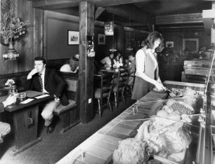 In einem Restaurant. Eine Frau bedient sich an der Obst- und Gemüsetheke. Aufgenommen 1973